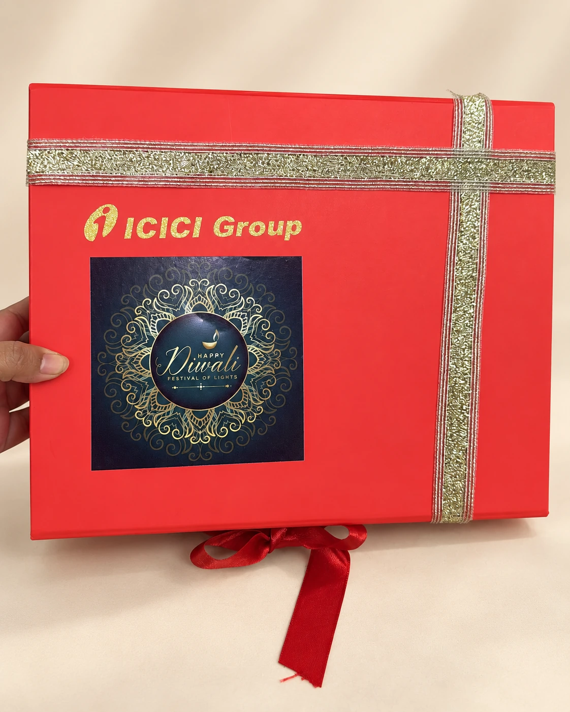 Red gift box with a gold ribbon and a company-branded Diwali card