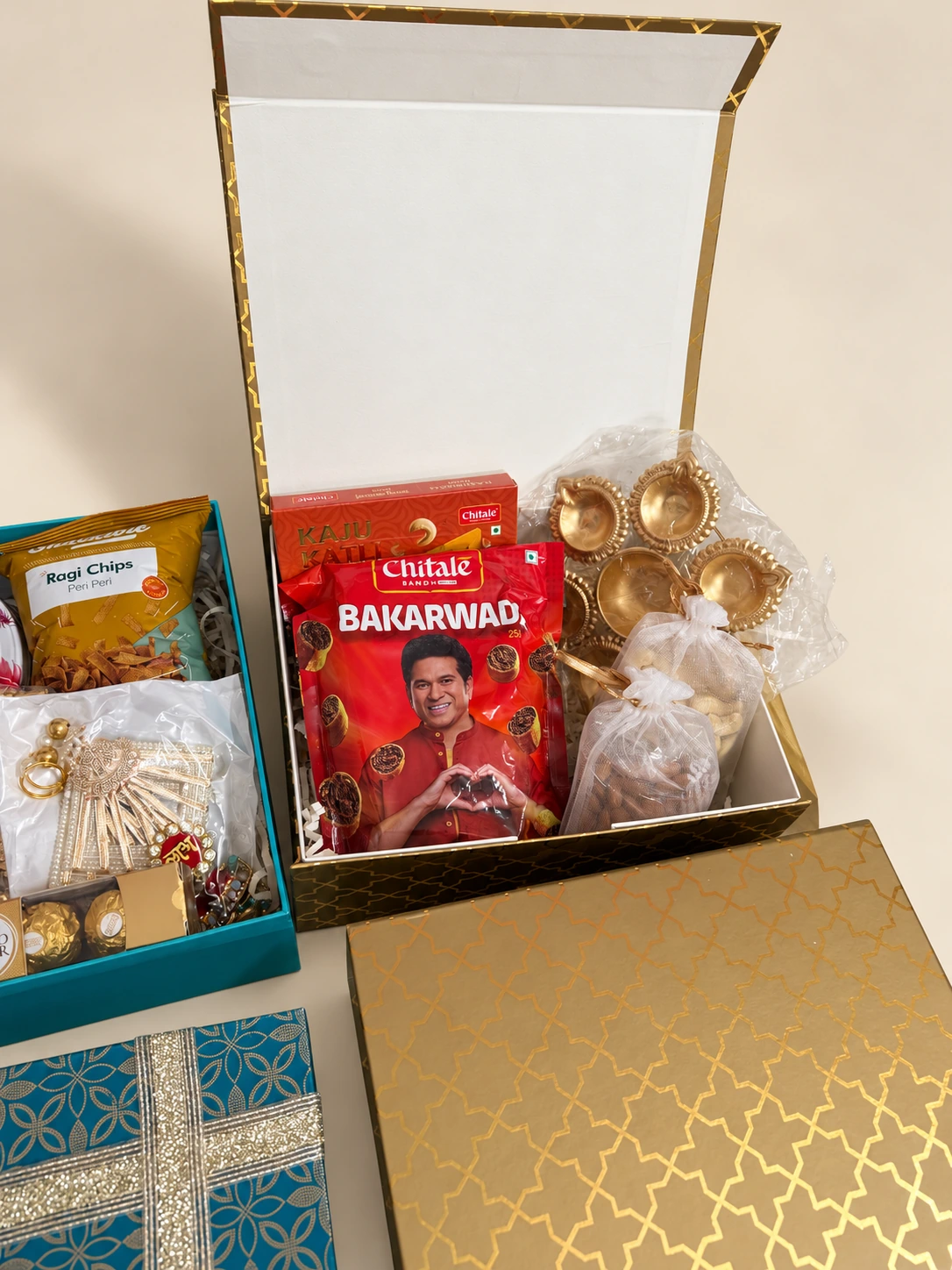 Gold patterned gift box with Maharashtrian snacks, diyas and dry fruits