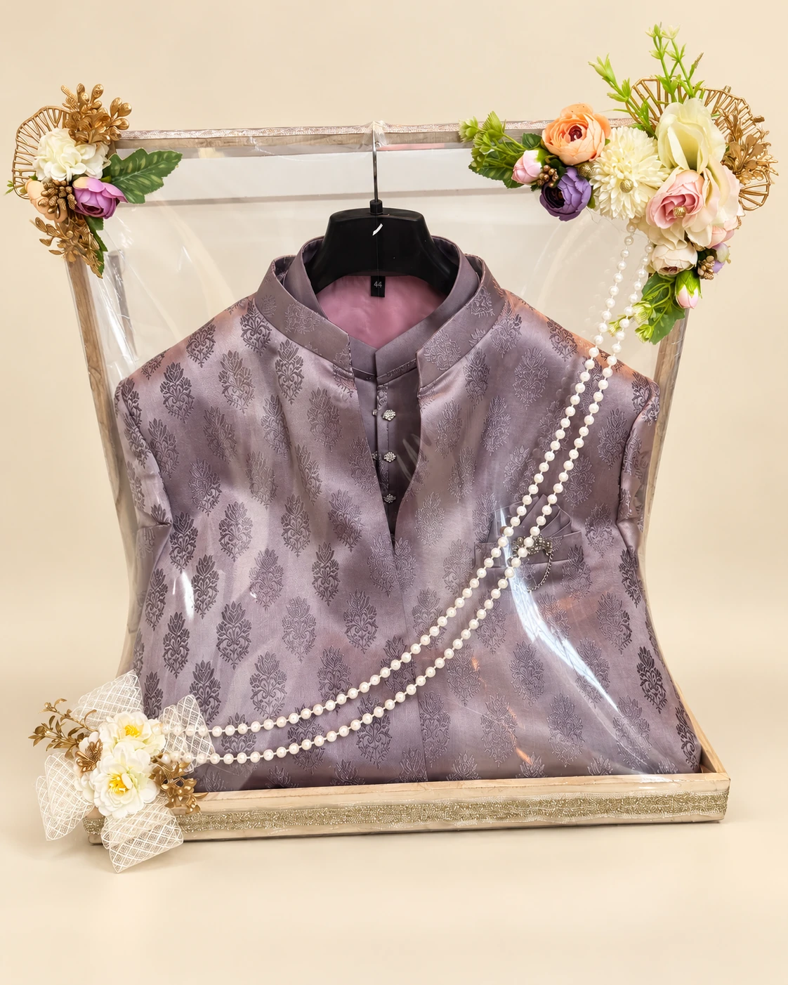 Lavender outfit on a hanger in a clear framed display with flowers and pearls