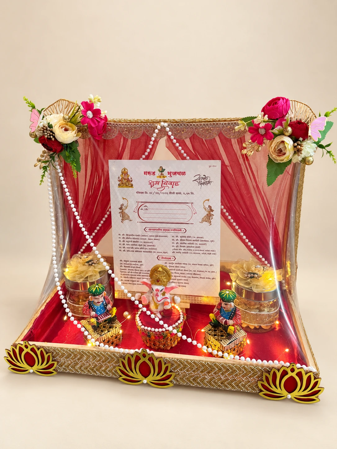 Red draped display with a wedding invitation, lotus details and pearl strings