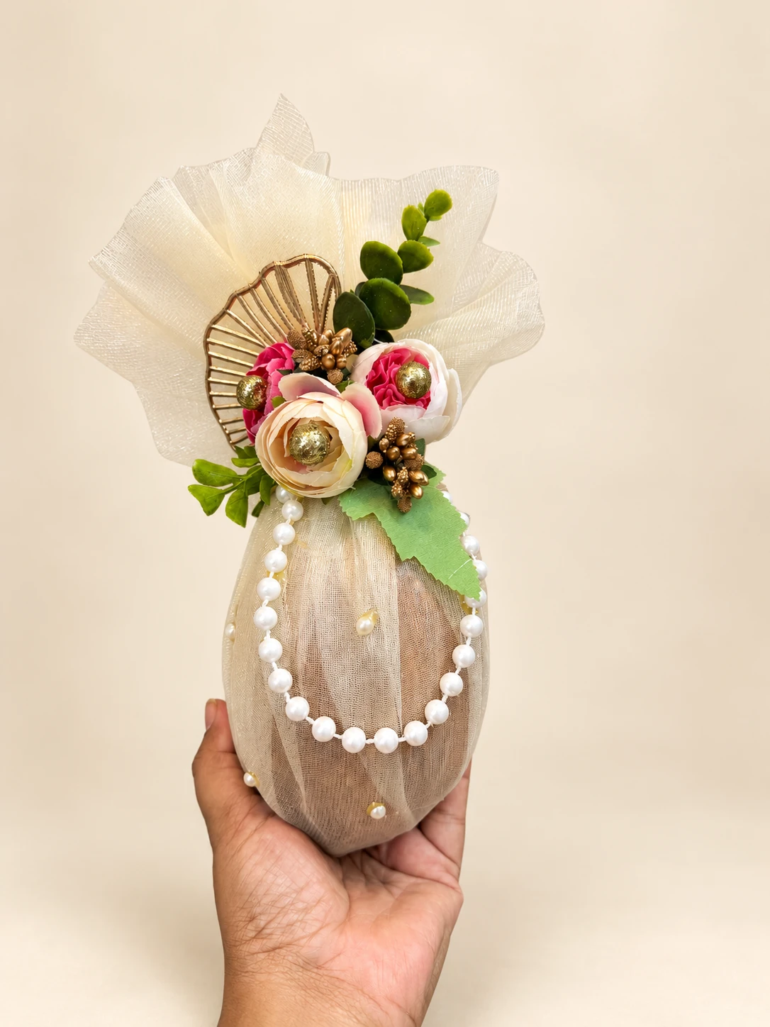 A coconut wrapped in cream net with roses and a pearl string